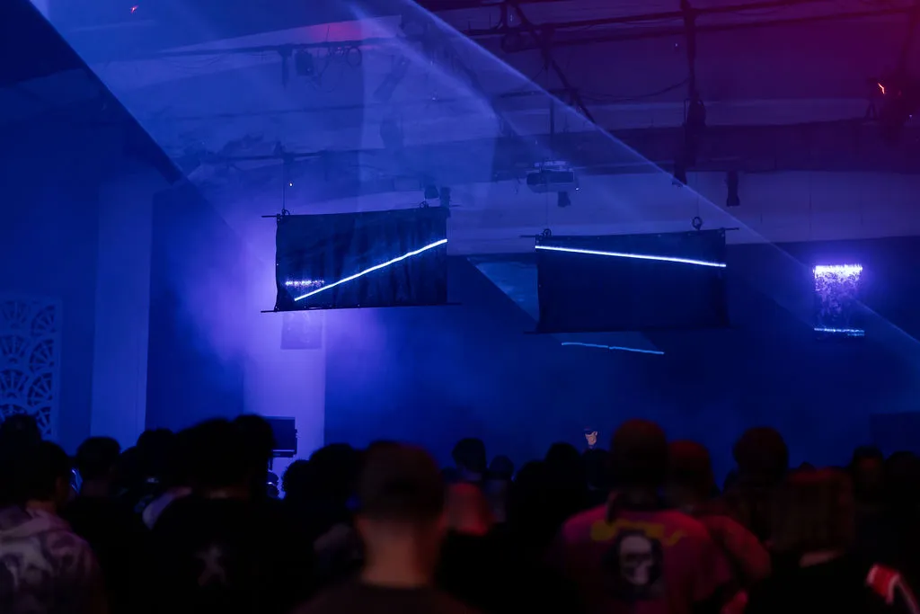 Tube lights and laser crossing reflective panels over the audience